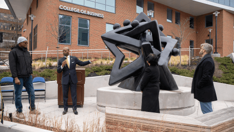 People standing around bronze sculpture, Community of Stars